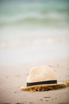 Nice straw hat laying on the sand. Beautiful ocean beach background. Outdoors Stock Photos