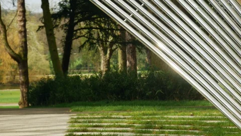 A nice sunny part of forest is behind an abstract patterned metal installation 스톡 동영상 105292847