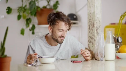Nice tattooed millennial guy staying up to date in social media app while eating Stock Footage 108796115