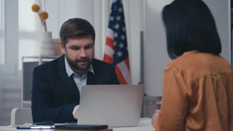 Nice US consular service employee checking computer data, issuing visa to woman Stock Footage 240837402