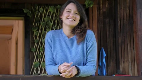 Nice Woman Stands On Veranda Smiling Enjoying And Looks Into Camera Stock Footage 252136200
