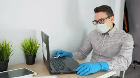 Nice worker man wear protective face mask, sitting, use laptop, in office room  Stock Footage 131470865