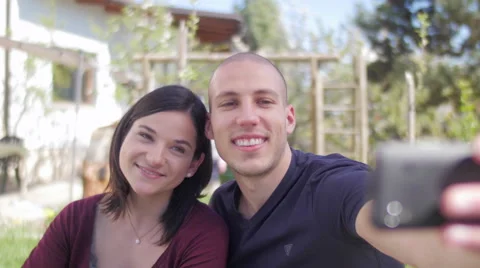 Nice young couple smiling and taking a selfie in front of the house Stock Footage 49833476