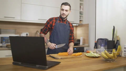 Nice young man in apron teaching how to cook online tutorial Stock Footage 143789083