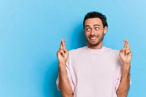 Nice young man with beard standing on blue background in white T-shirt, looking Stock-Fotos
