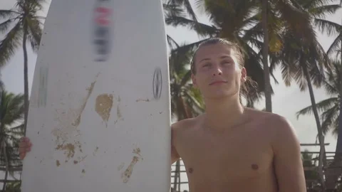 Nice young surfer with a good physique stands on the beach Stock Footage 73826838