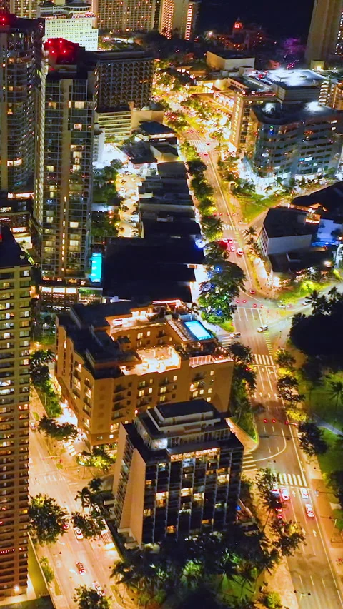 Night aerial of Honolulu with rooftop pool and city lights. Vertical video. Stock Footage 319760187