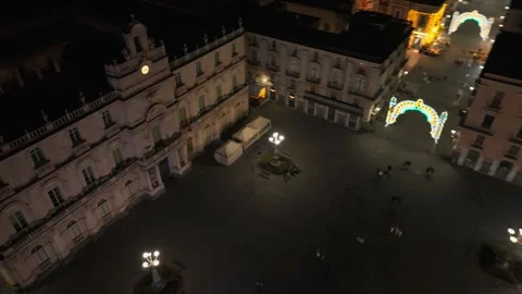 Night aerial over Catania square with a clocked historic facade in Sicily Stock Footage 345100660