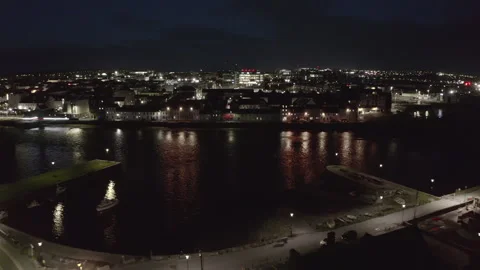 Night Aerial Pullback of Long Walk Over Water with Galway City Lights Stock Footage 292555208