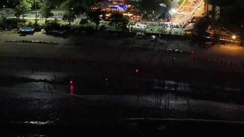Night beach scene with people walking along shore and lights in background Stock-Footage 342332875