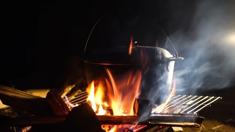 Night bonfire. Dinner is cooked in pots over open fire Stock-Footage 94854836