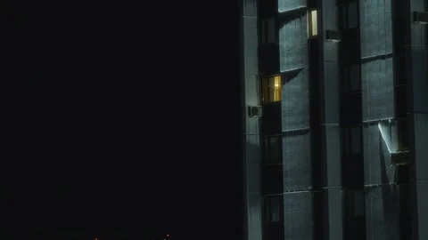 Night building facade with glowing window and person silhouette Stock Footage 315743220