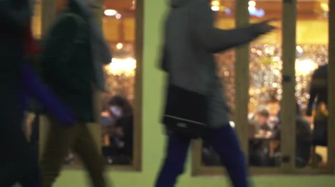 Night cafe through window from street with pedestrians in night city. Blured Stock Footage 68740571