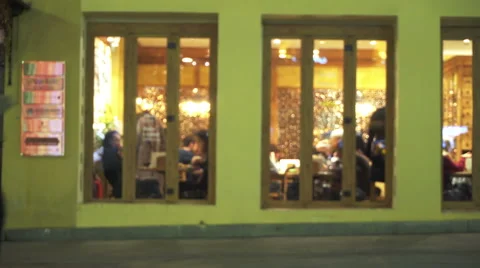 Night cafe through window from street with pedestrians in night city. Blured Stock Footage 68740646