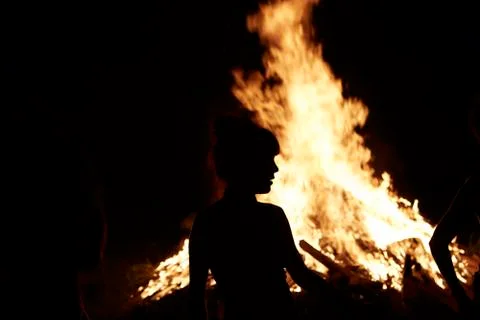 Night campfire with woman silhouette in front of fire Stock Photos