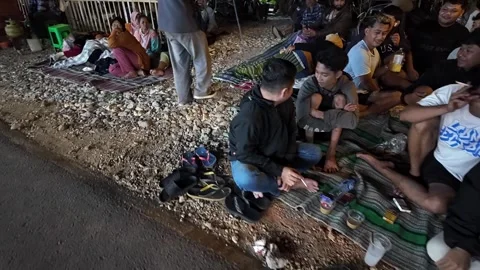 Night Carnival Crowd Relaxing On Roadside Mats Stock Footage 345202201