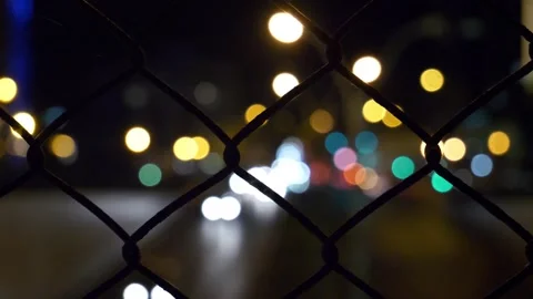 Night City Lights Blurred Through a Chain Link Fence Stock Footage 295745378