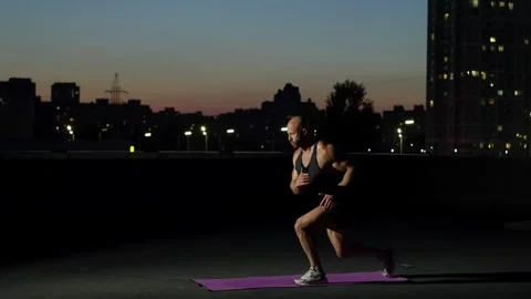 In the night city, a man performs a leg kick exercise with a jump. Stock Footage 248178426