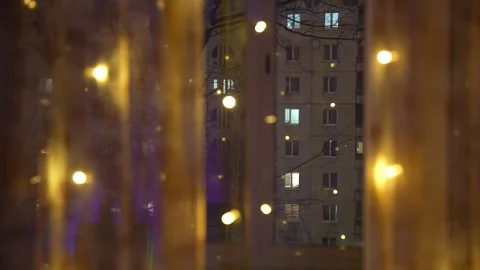 Night city view through window with warm glowing lights on curtains Stock Footage 325802393