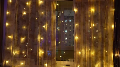 Night city view through window with warm glowing lights on curtains Vídeos de archivo 325802414