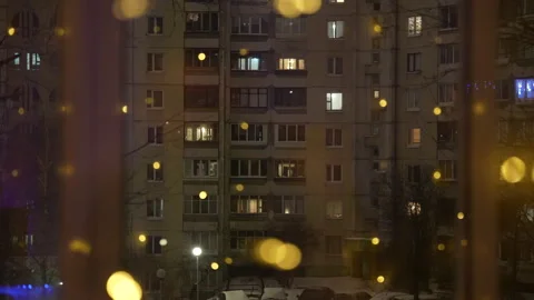 Night city view through window with warm glowing lights on curtains Stock Footage 325802443