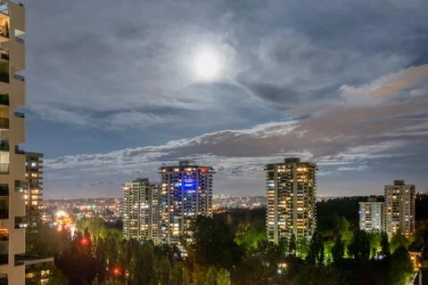 Night cityscape with full moon in clouds Foto stock