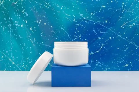 Night cream in white opened jar on blue podium against abstract blue background Stock Photos