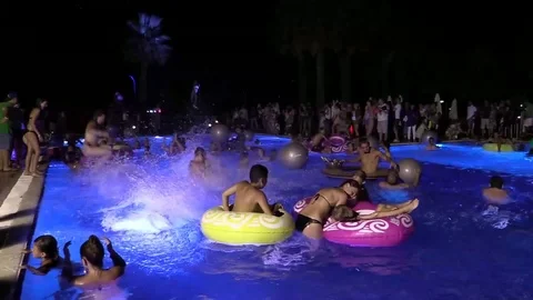 Night crowd active outdoor poolside party pool jump. Slow motion Stock Footage