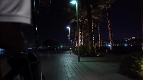 Night cyclist glides past palm trees 스톡 동영상 337764019