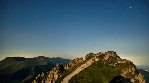 Night to dawn timelapse over mountain summit with cross under starlit sky and Vidéo 319842415