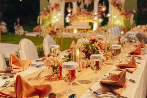 Night dinner long table with white table cloth and an elegant floral arrang.. Stock Photos