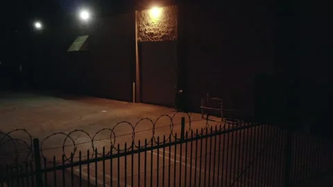 Night Drone Aerial View of Razor Wire Fenced Warehouse Los Angeles California Vidéo 145919974