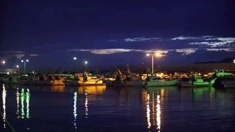 Night, evening, several boats floating on the harbor's sea, sparkling lights and Stock Footage 251699113