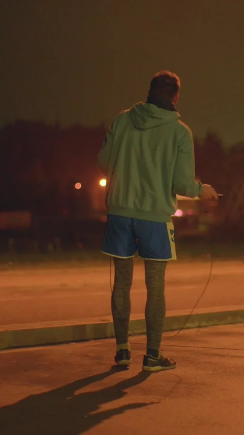 Night exercise on lit street emphasizing strength and resilience Stock Footage 324592761