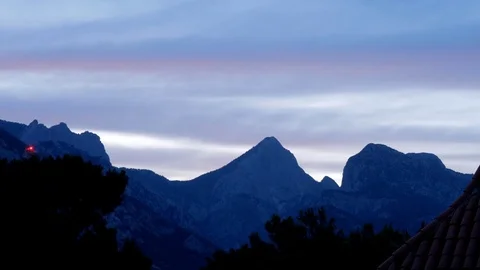 The night falls in a mountain valley. The clouds change color from multicolored Stock Footage 76472324