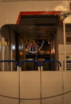 Night ferry passage frames a lit Ferris wheel across the water Stock Photos