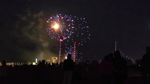 Night Fireworks Under the Moon and Crowd of Spectators Against City Lights .. Stock Footage 341609313