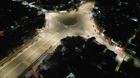 Night flyover: Large illuminated street roundabout with scooter traffic Stock Footage 336522995