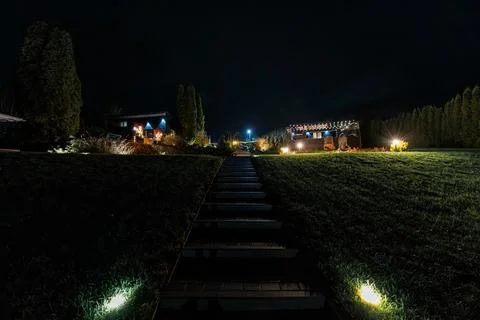 Night garden path and string lit terrace with modern houses Stock Photos