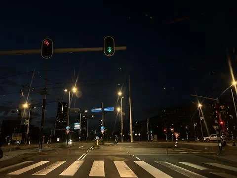 Night intersection at dusk with glowing traffic signals, tram overhead wires Stock Photos