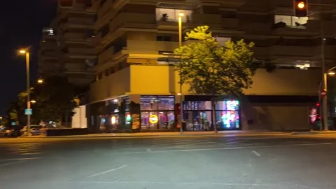 Night intersection with illuminated buildings and traffic lights in Madrid Видео 338195068