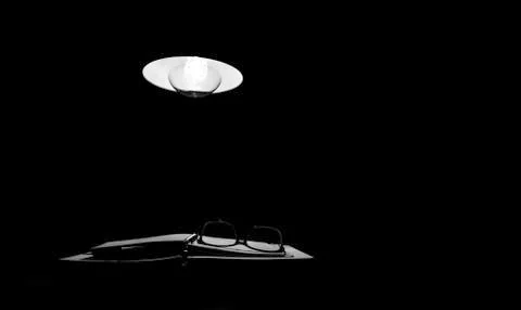 At night the light from the lamp falls on the notebook and reading glasses Stock Photos