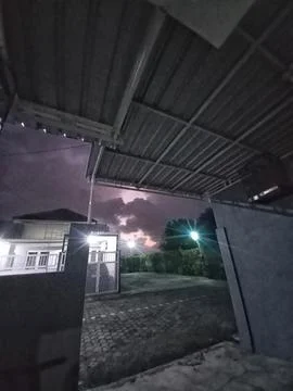 Night Lightning Flash Behind Dark Clouds in Residential Area 写真素材