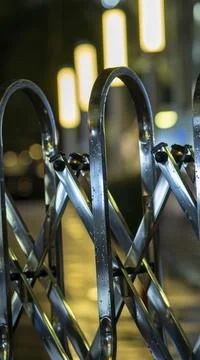 Night lite soft focus back grounds over metal railing and rain drops Stock Photos