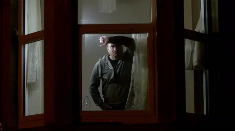 In the night a man leaned at a bow window looks pensive and thoughtful, lonely Stock Footage 59938928