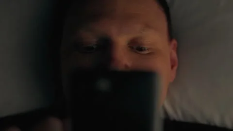 Night phone. A young guy in home clothes is involved in the process of tired Stock Footage 252755145