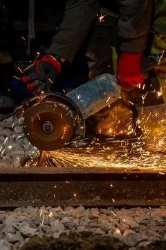 Night rail cutting with angle grinder and sparks on track ballast Stock Photos
