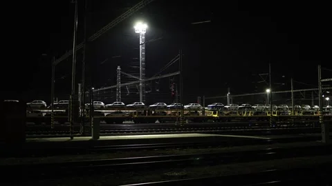Night railway yard with freight wagons loaded with cars illuminated by industria Stock Footage 319242915
