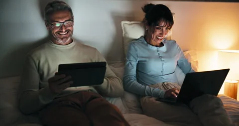 Night, remote work and couple with tech in bedroom, creative and plan for ebook 動画素材 335535601
