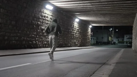 A Night Runner Pacing Underneath the Urban Overpass in a Vibrant City Setting at Stock Footage 307435474